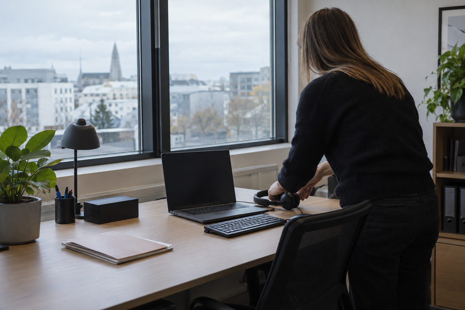 An HR administrator prepares a new employee’s laptop and headset at a workstation in Reykjavík, Iceland.